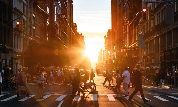 People walking through the busy intersection at 5th Avenue and 23rd Street in New York City on a summer day with sunset flare between the background buildings People walking through the busy intersection at 5th Avenue and 23rd Street in New York City on a summer day with sunset flare behind the background buildings bustling city stock pictures, royalty-free photos & images
