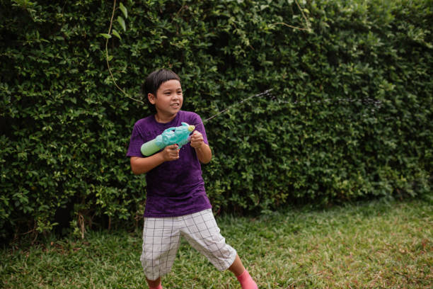 Boy is splashing with a water gun in the yard.