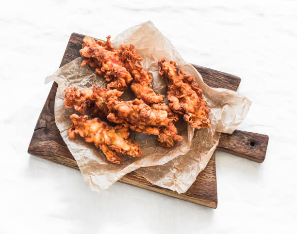 istock Deep-fried chicken breast pieces in batter - delicious snack, tapas on a cutting board on a light background, top view 2151980089