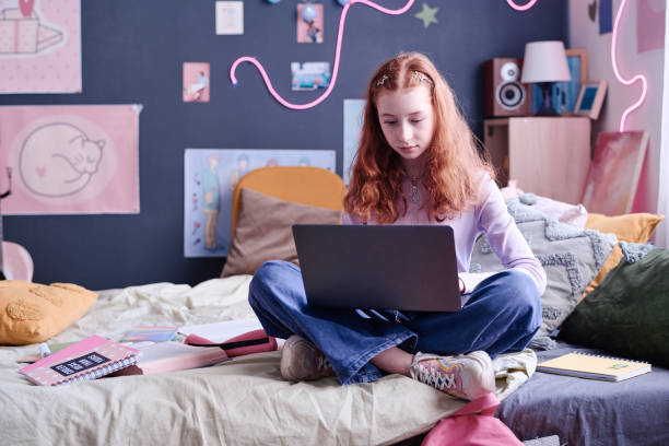 istock Schoolgirl Sitting On Bed Using Laptop 2151989624