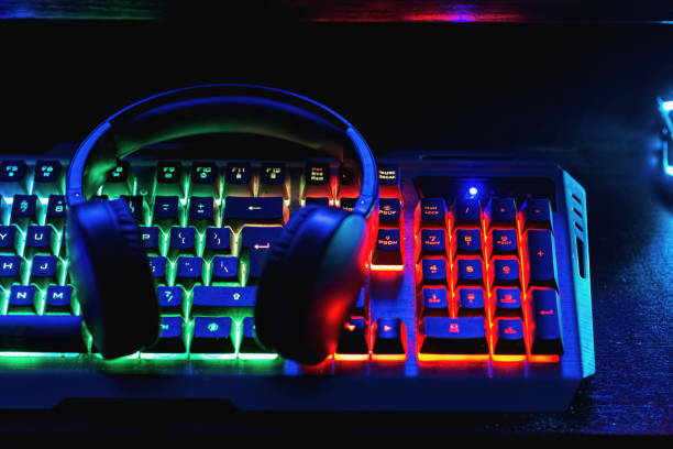 istock Pro gaming illuminated desk, headset, keyboard, computer neon lights. Cyber sport equipment laying on desktop, ready for online video gaming.Dark shot. 2151990528