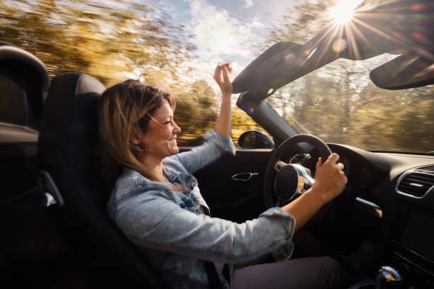 istock Happy woman driving a convertible car in blurred motion. 2151990689