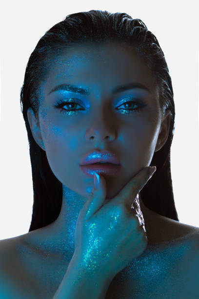 istock Womans face bathed in blue light, her skin adorned with sparkling glitter, exudes a contemplative look 2151990870