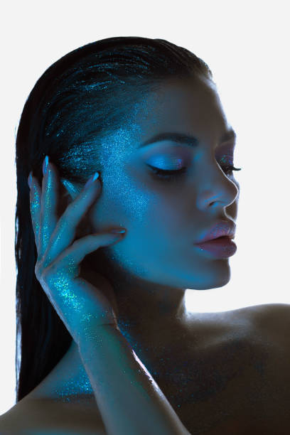 istock Woman with shimmering blue-tinted skin strikes a tranquil pose under cool lighting 2151990875