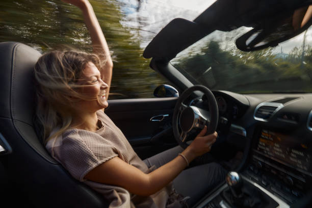 istock Young cheerful woman having fun while driving a convertible car. 2151990988
