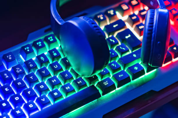 istock Pro gaming illuminated desk, headset, keyboard, computer neon lights. Cyber sport equipment laying on desktop, ready for online video gaming.Dark shot. 2151991801