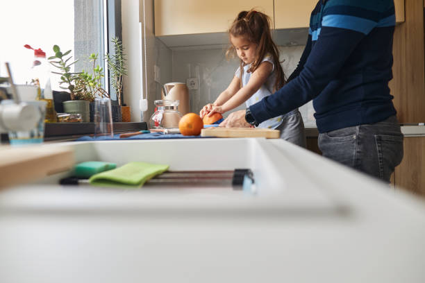 istock Young girl stands at the kitchen table making juice with her father 2151993229