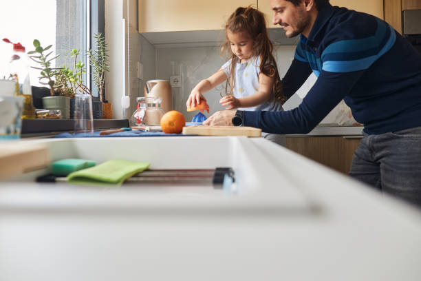 istock Young girl stands at the kitchen table making juice with her father 2151993235
