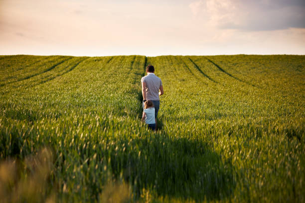 Young father and daughter in field on a sunset. Single father is running with little girl.