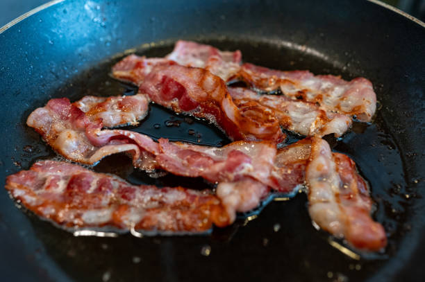 istock Frying bacon slices in frying pan on stove 2151996915