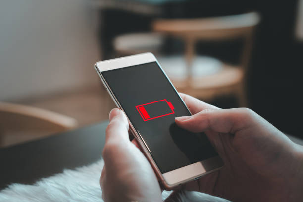 istock Smartphone low power, needs charging. Close up of man's hand uses a smartphone that displays a critically low battery warning alert. 2151997588