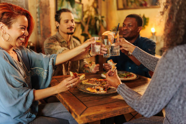 istock Four young people toasting while sitting in restaurant 2152001465