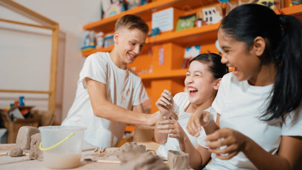istock Student playing with friend while put the clay on shirt at class. Edification. 2152003748