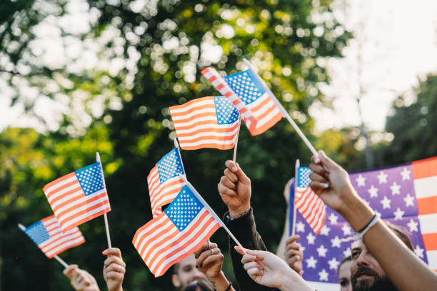 A group of people is waving small American flags at sunset