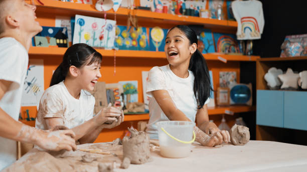 istock Girl modeling cup of clay while looking at smart boy at art class. Edification. 2152004832