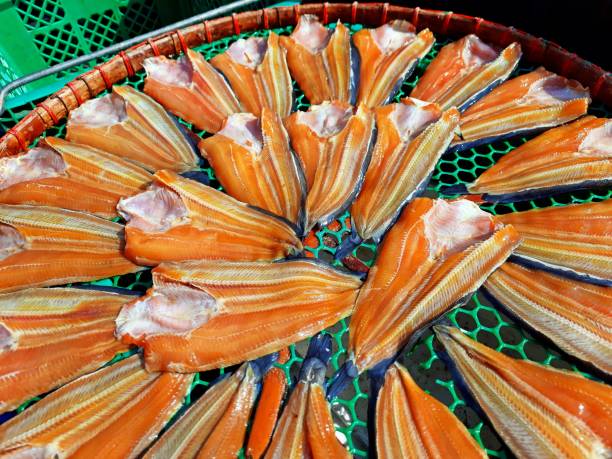 Dried fish by sunlight, blue sky background. Natural food preservation. Dried fish for cooking.