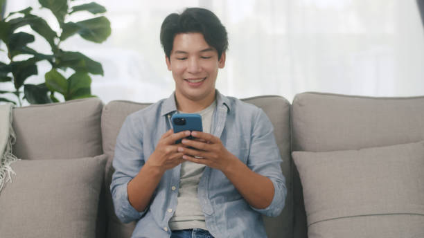 istock Happy Young Man Texting on Smartphone at Home. 2152007073