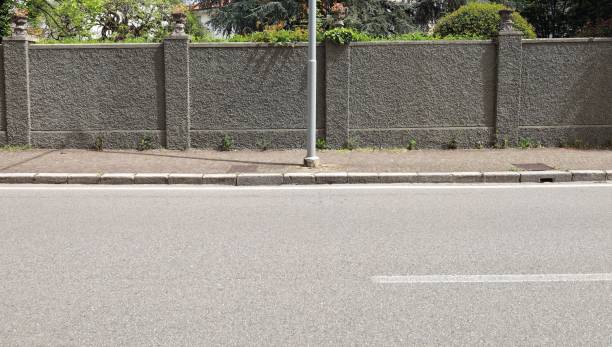 istock Pole on sidewalk with a long rough concrete wall on behind.  street in front 2152008236