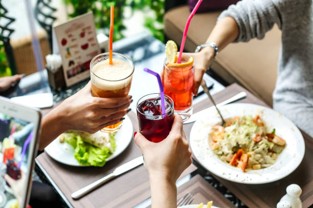 A diverse group of individuals sitting together at a table, socializing while holding their beverages.