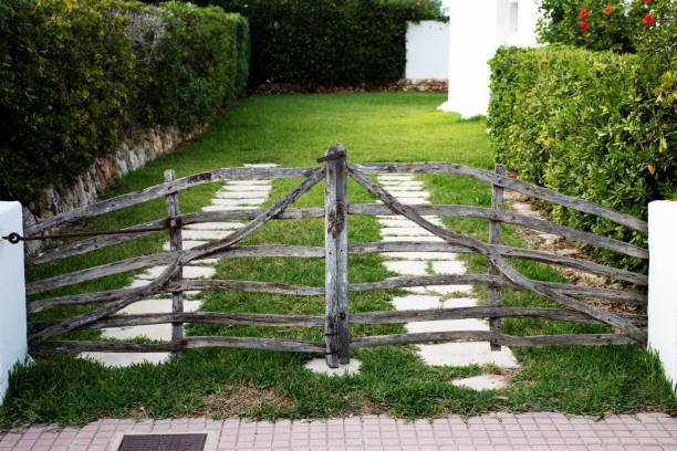 Old wooden gate in a mountain meadow with tall grass and trees in the background. Rural rustic charm in Tara National Park, Serbia.