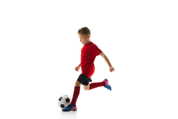 istock Little athlete boy, training dribbling ball and passing in motion against white studio background. Young soccer player. 2152030351