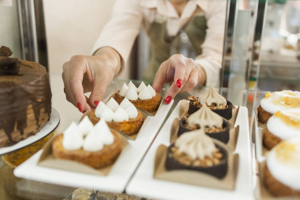 istock Sweet Temptations: Unrecognizable Woman Arranges Cakes in Coffee Shop Window 2152038407