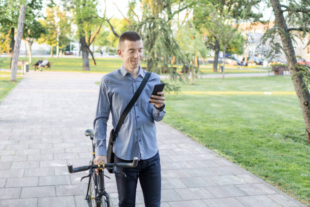 istock Smiling businessman commuter using mobile phone. He is enjoying at public park on his bicycle trip from work after a long workday. Sustainable concept of going to work by an electric bicycle 2152039957