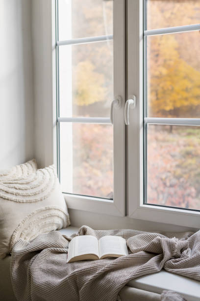 istock Cozy sitting place on window sill with cushions, soft plaid and open book 2152046665