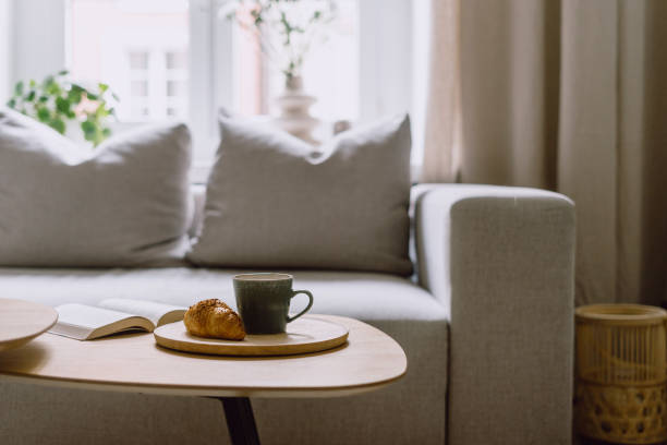 Selective focus on bamboo tray with cup, bakery and book on coffee table