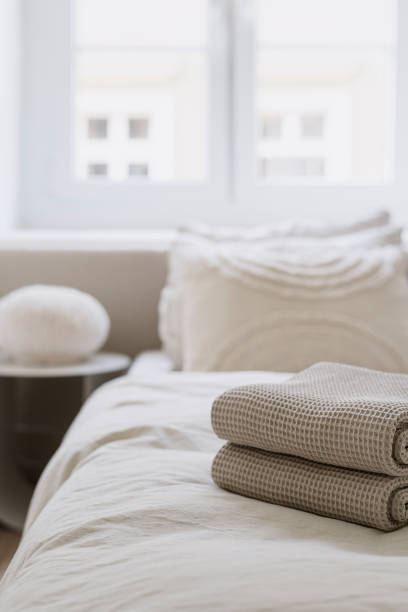 istock Selective focus on stack of fresh soft beige towels on comfortable bed with bedding 2152046781
