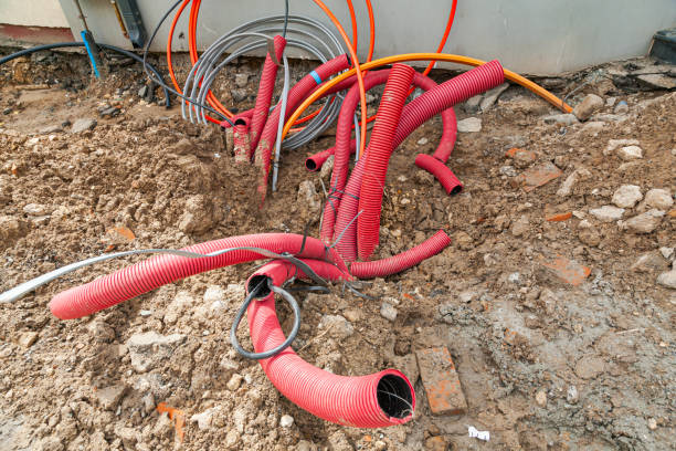 Laying communications in the ground using red corrugated hoses.
