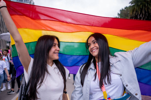 istock Lesbian couple looking at each other while holding the rainbow flag during a parade 2152048505