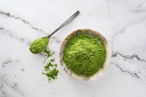 Barley grass or matcha, organic chlorella and spirulina powder in bowl and spoon. Barley grass or matcha, organic chlorella and spirulina powder in bowl and spoon on marble background, top view, herbal medicine concept. chlorella stock pictures, royalty-free photos & images