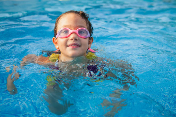 istock Smiling girl with swimming goggles in pool, copy space 2152056215