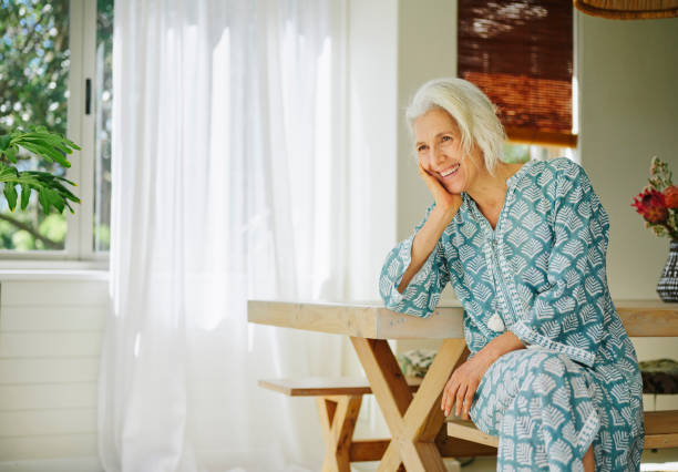 istock Laughing mature woman sitting alone at a table at home 2152060652