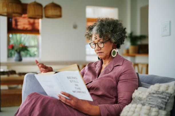 istock Mature woman reading a book on her sofa at home 2152061199