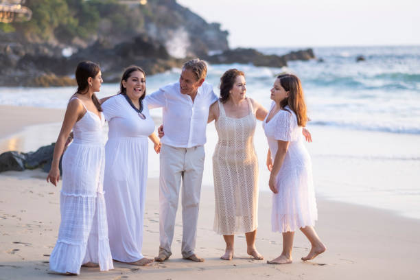 Three senior female friends enjoying leisure time on beach. Mature women friends discussing and laughing on sea coast. Relaxed retired women spending vacation together
