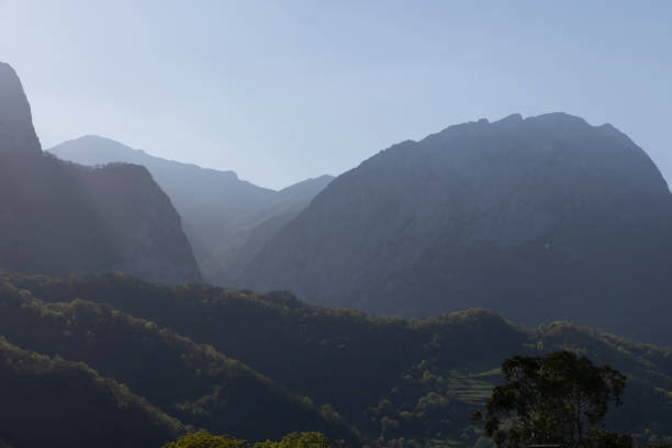 Mountain landscape with peak and cloud on a bright sunny spring day with green vegetation and blue sky in Picos de Europa National Park in the north of Spain.