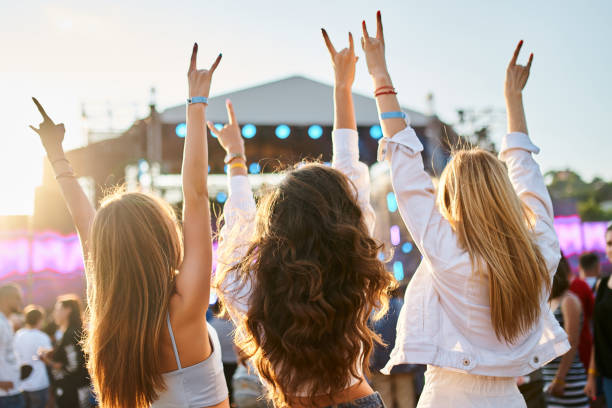 gruppe von freundinnen, die live-musik auf dem sonnigen strandfestival genießen. mädchen tanzen, feiern mit erhobenen händen in sommerstimmung. zwangloser spaß, jugendkultur, outdoor-event auf dem seeweg. freundschaft, lifestyle-moment. - musikfestival stock-fotos und bilder