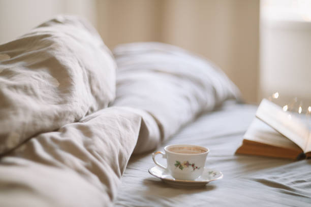 istock Light cozy bedroom, Coffee or tea cup and an open book on the bed. Spring still life. Breakfast in bed. 2152066858