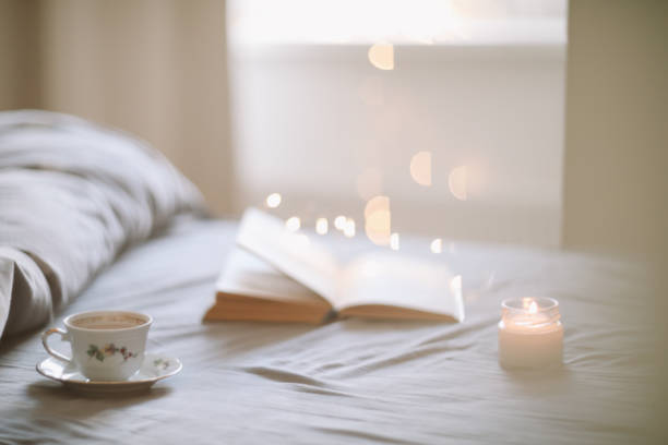 istock Light cozy bedroom, Coffee or tea cup and an open book on the bed. Spring still life. Breakfast in bed. 2152067421