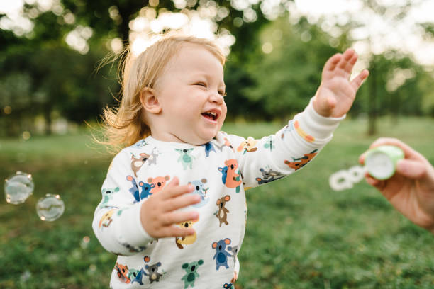 Boy catches soap bubbles in nature. Toddler little cute walking and playing in spring garden. 2 year old boy on green grass in park on enjoying sunny summer day. Outdoors creative activities for kids. niño atrapa pompas de jabón en la naturaleza. niño pequeño lindo caminando y jugando en el jardín de primavera. niño de 2 años en la hierba verde en el parque en disfrutar de un día soleado de verano. actividades creativas al aire libre para niños