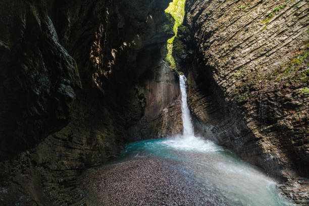 The stunning Kozjak Waterfall cascades into a serene blue pool, surrounded by a verdant cliffside setting.