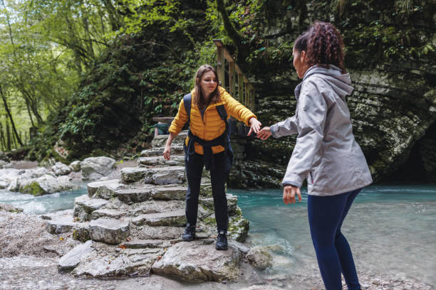 istock Female Friends Helping Each Other While Hiking in Forest 2152070809