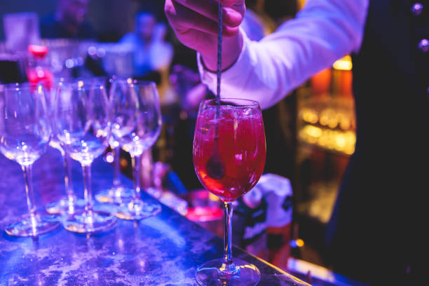 istock Bartender working, beautiful row line of different coloured liquor alcohol cocktails on a party in a bar, and others on catering banquet on event, barman mixing drinks and beverages in a club 2152074152