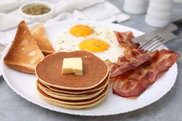 istock Tasty pancakes served with fried eggs and bacon on grey table, closeup 2152076020