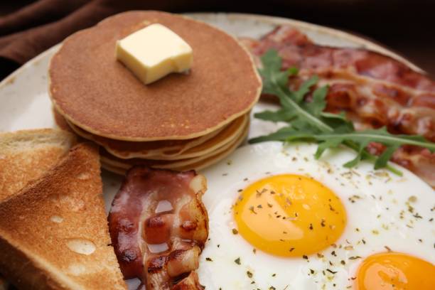 istock Tasty pancakes with fried eggs and bacon on plate, closeup 2152076079
