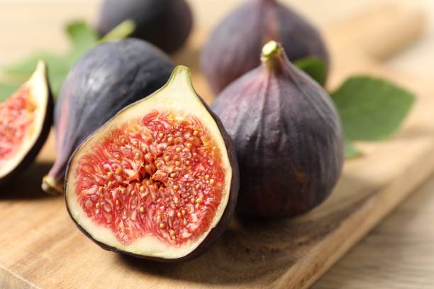 istock Whole and cut ripe figs on wooden table, closeup 2152076102