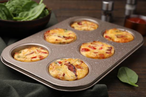 istock Freshly baked bacon and egg muffins with cheese in tin on table, closeup 2152076106