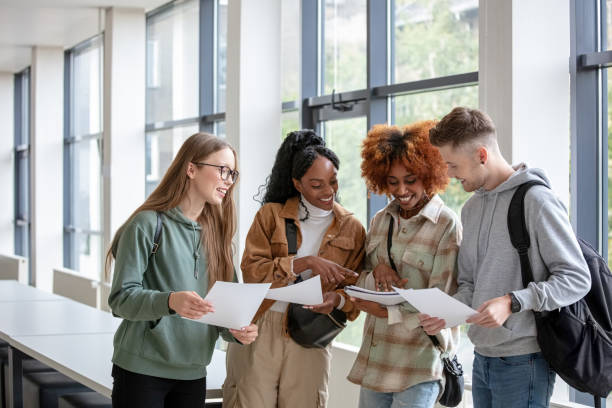 University students discussing exam results Multiracial students standing in the corridor at university and discussing educational test results. educational test results stock pictures, royalty-free photos & images